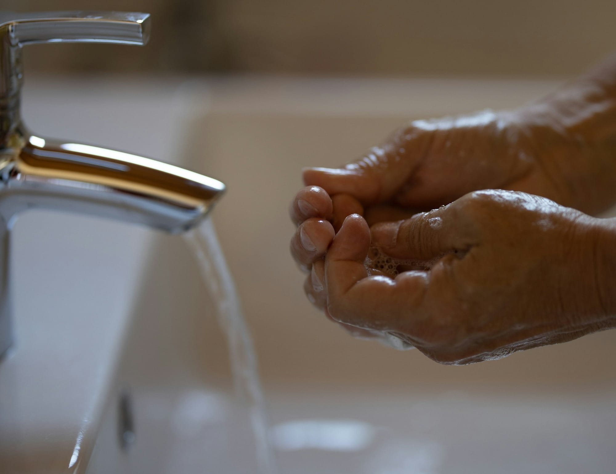 person washing hands on faucet